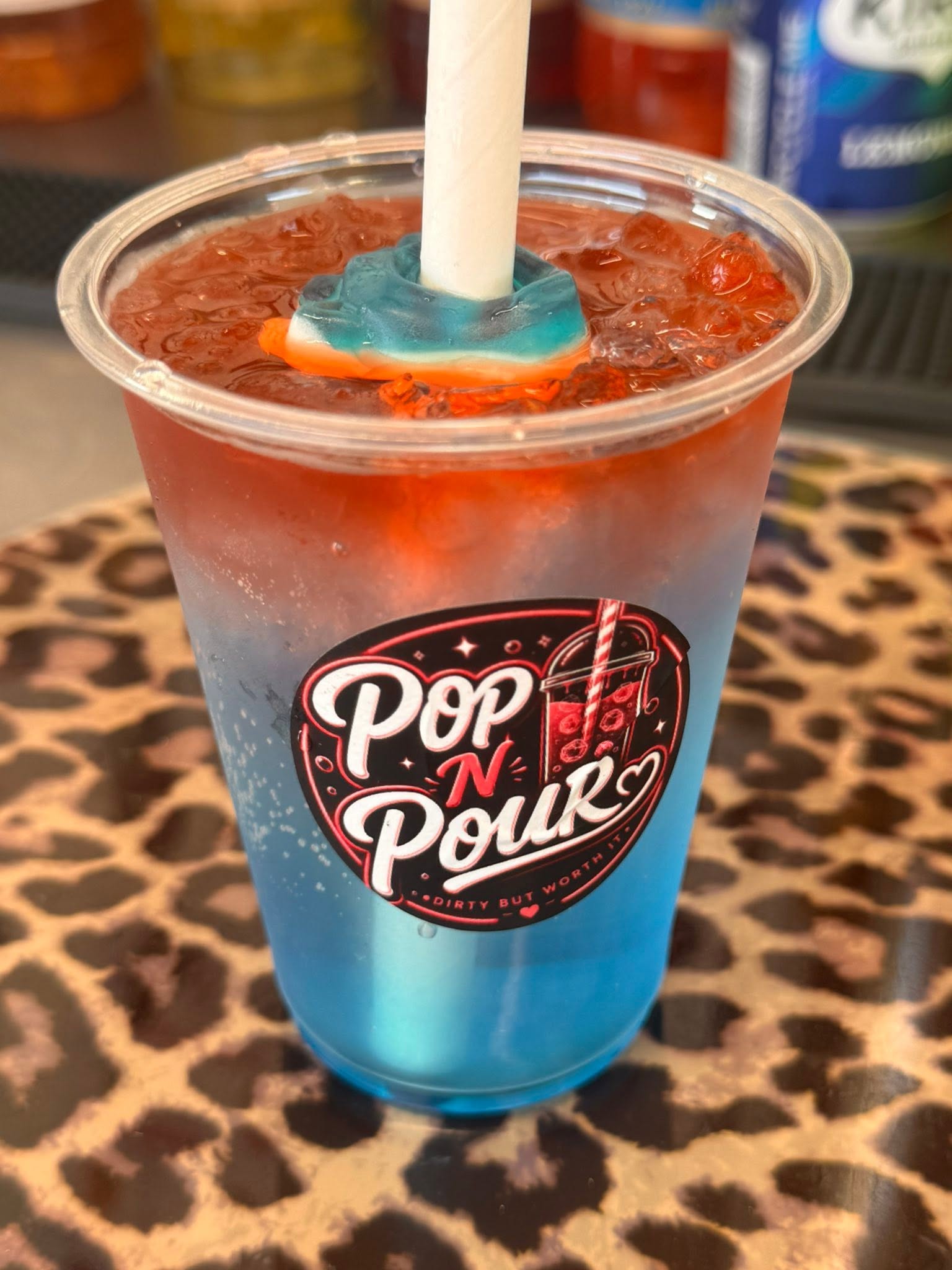 A colourful blue and red Pop N Pour soda with a lolly on top